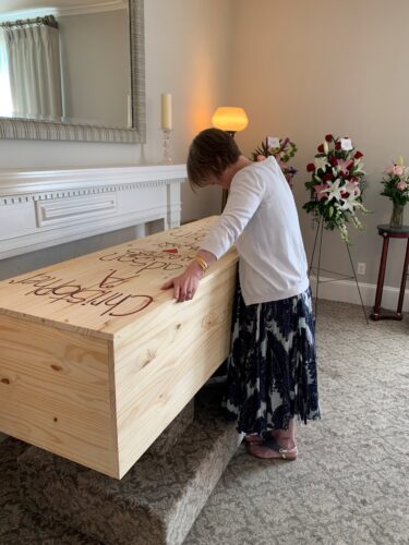 Tina Harris stands over the casket that contains the remains of her son, Christopher, and daughter Sarah. The pair were buried together after passing away just weeks apart in 2022. (Credit: Harris Family)