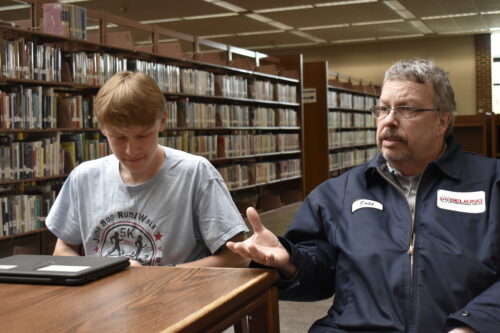 Todd Dwenger explains how his home internet often pushes him to drive his son Tyler Dwenger into town to use the wireless internet at the public library. Photo by Mitchell Lierman.