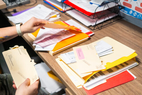 Emily Meyer flips through medical and utility bills March 27, 2025, in her office at the Dubois County Community Corrections Center in Jasper, Indiana. Meyer kept some bills in her home and stored some in a box under her desk at work. (Photo by Alayna Wilkening)