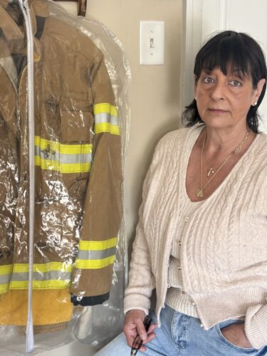 Whistleblower Diane Cotter stands with the turnout gear her husband wore that kicked off a decade-long advocacy effort to raise awareness about the PFAS contained in firefighter protective equipment.